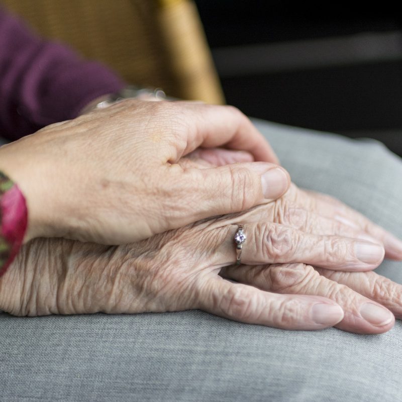 Younger person with their hand on an older persons' hands